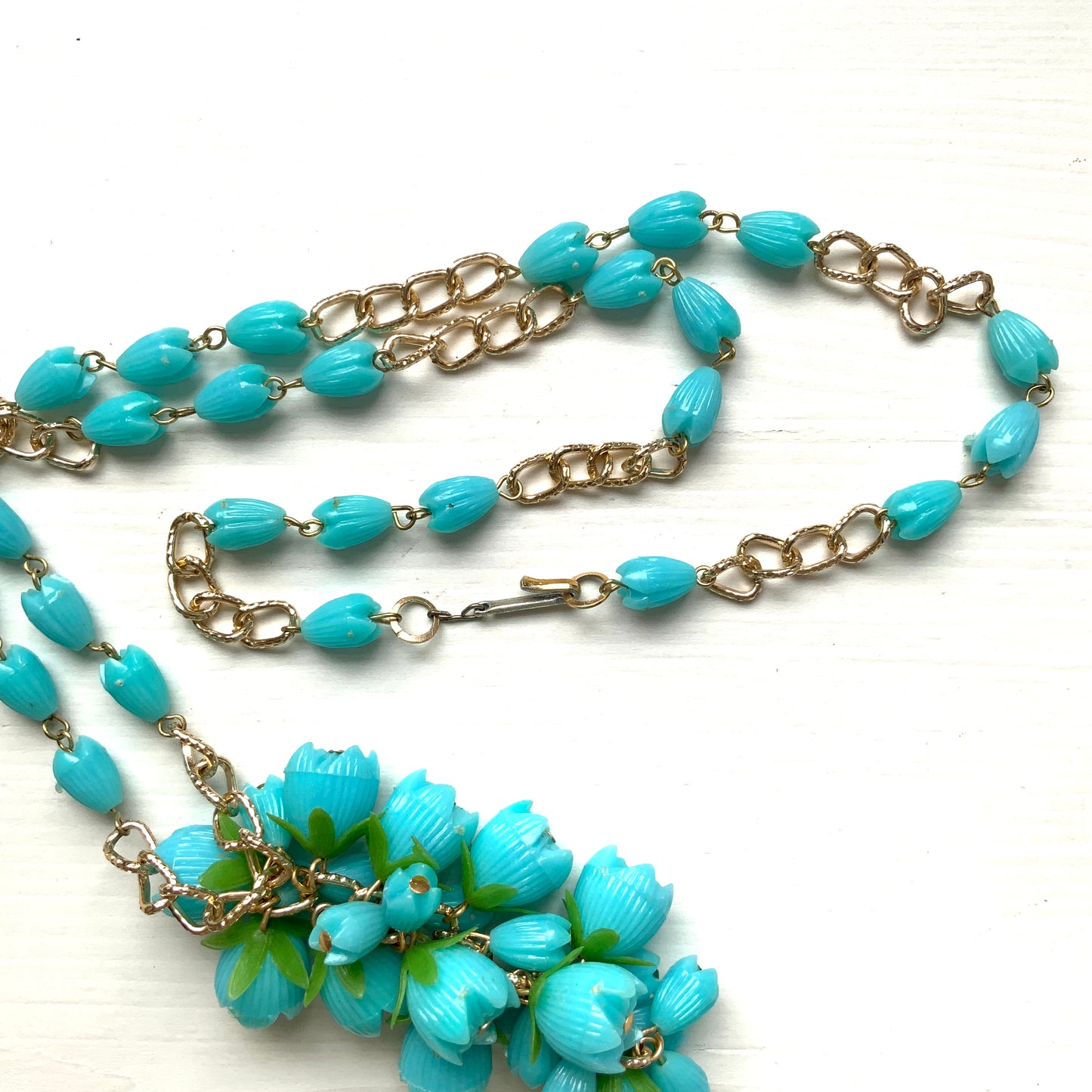 A vintage necklace featuring turquoise blue plastic flower beads that sway beautifully at the neckline.  ターコイズブルーのプラスチックフラワービーズが胸元で揺れるヴィンテージネックレス。