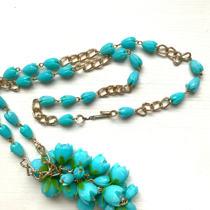 A vintage necklace featuring turquoise blue plastic flower beads that sway beautifully at the neckline.  ターコイズブルーのプラスチックフラワービーズが胸元で揺れるヴィンテージネックレス。