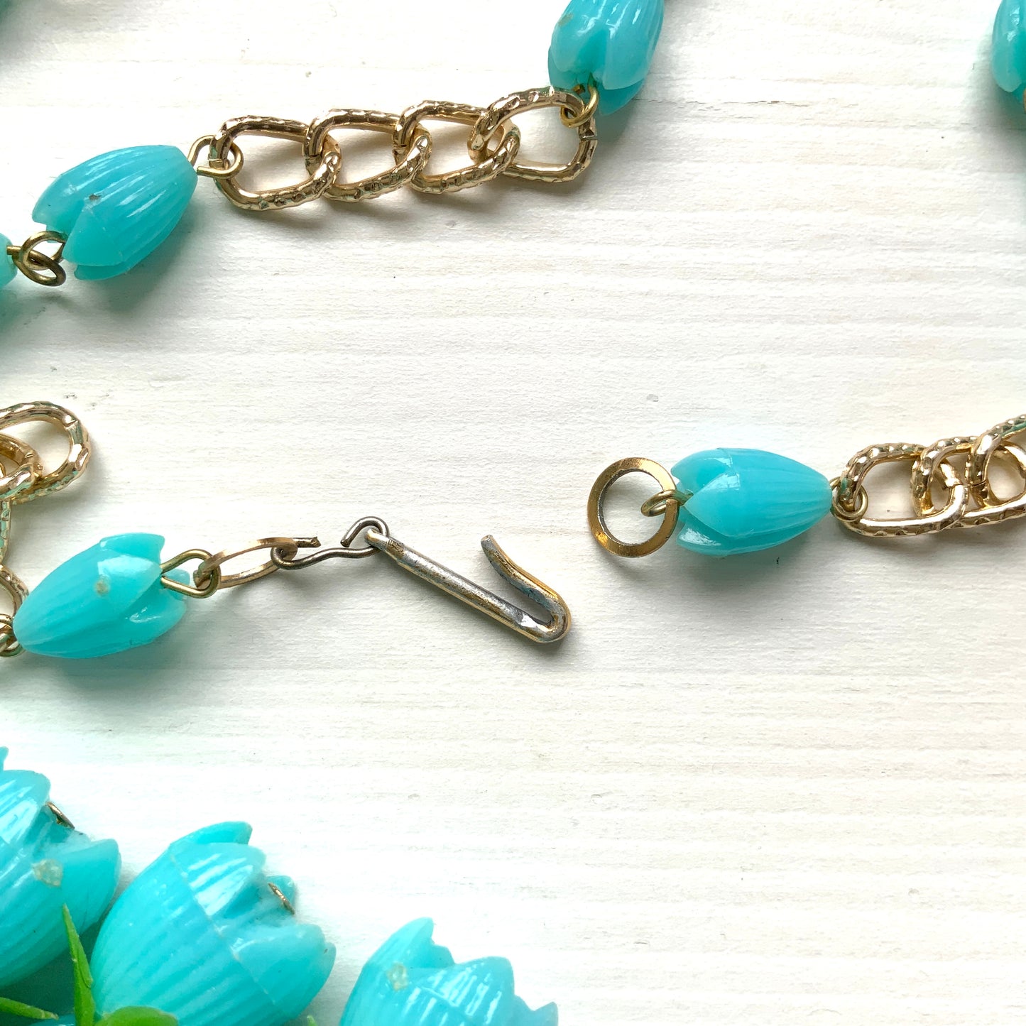 A vintage necklace featuring turquoise blue plastic flower beads that sway beautifully at the neckline.  ターコイズブルーのプラスチックフラワービーズが胸元で揺れるヴィンテージネックレス。