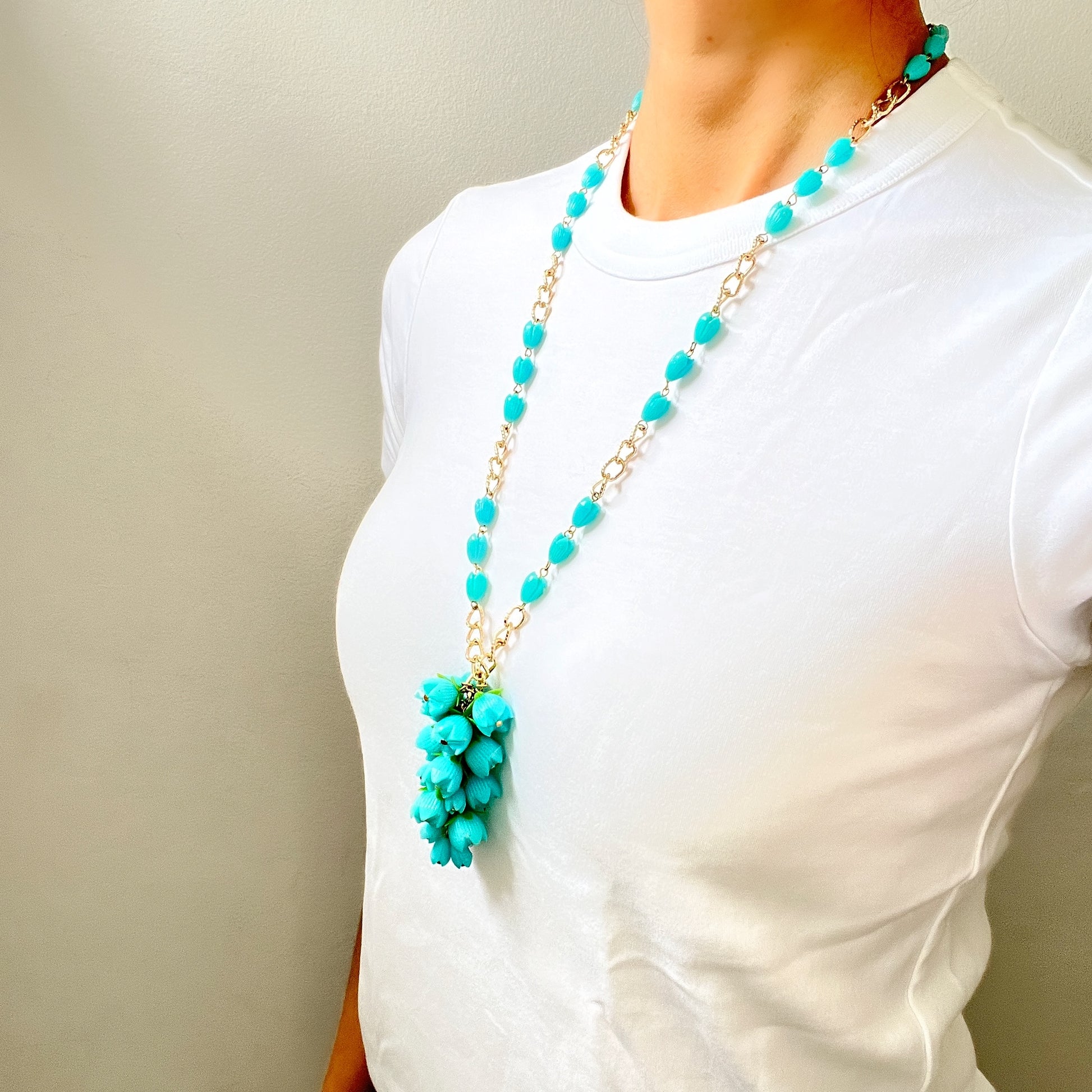 A vintage necklace featuring turquoise blue plastic flower beads that sway beautifully at the neckline.  ターコイズブルーのプラスチックフラワービーズが胸元で揺れるヴィンテージネックレス。