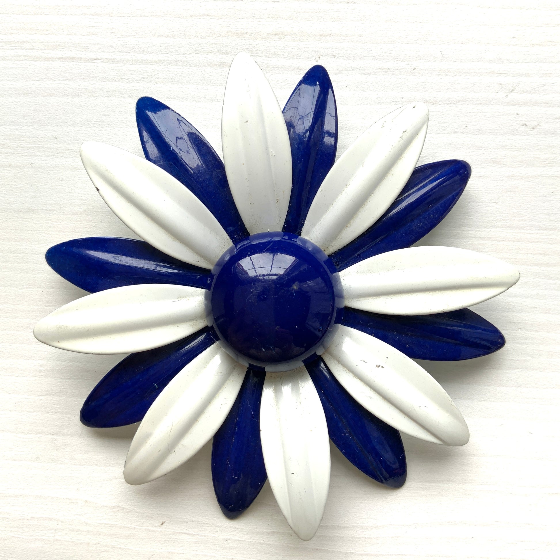 An oversized flower brooch in navy blue and white enamel. ネイビーブルーとホワイトのエナメルを使用した、大ぶりのフラワーブローチ。