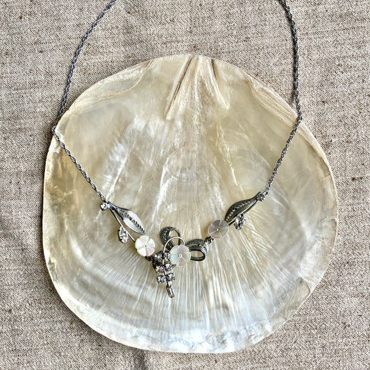 A charming necklace featuring tiny mother of pearl flowers, silver-tone filigree leaves, and clear rhinestone accents. かわいらしいマザーオブパールの小さなお花と、シルバートーンのフィリグリーやクリアラインストーン のリーフのネックレス。
