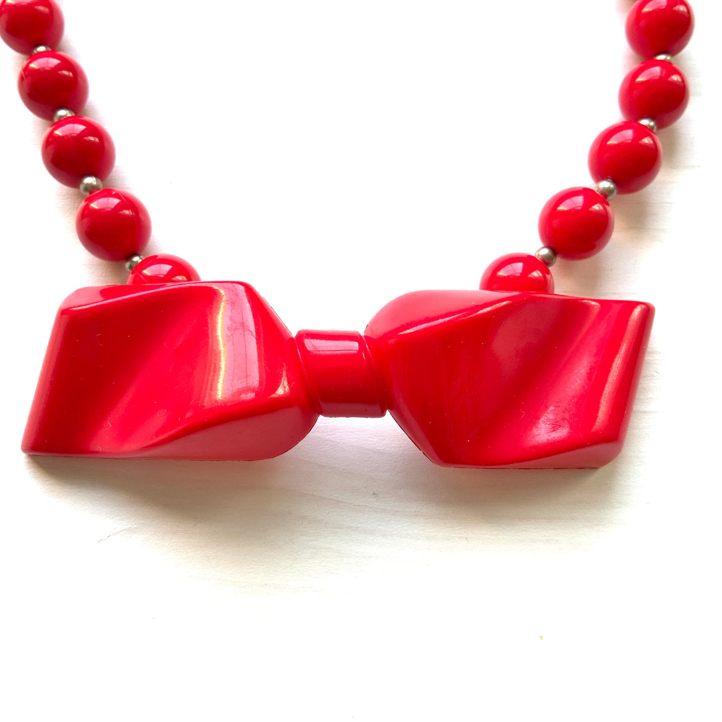 Vintage necklace featuring bright red plastic beads and a bow motif. 鮮やかなプラスチックのレッドビーズとリボンモチーフのネックレス。