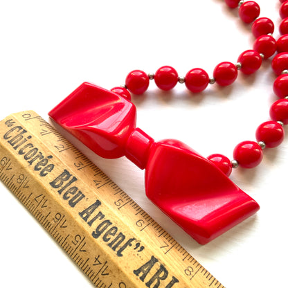 Vintage necklace featuring bright red plastic beads and a bow motif. 鮮やかなプラスチックのレッドビーズとリボンモチーフのネックレス。