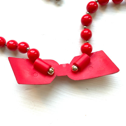 Vintage necklace featuring bright red plastic beads and a bow motif. 鮮やかなプラスチックのレッドビーズとリボンモチーフのネックレス。