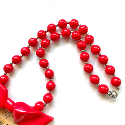 Vintage necklace featuring bright red plastic beads and a bow motif. 鮮やかなプラスチックのレッドビーズとリボンモチーフのネックレス。
