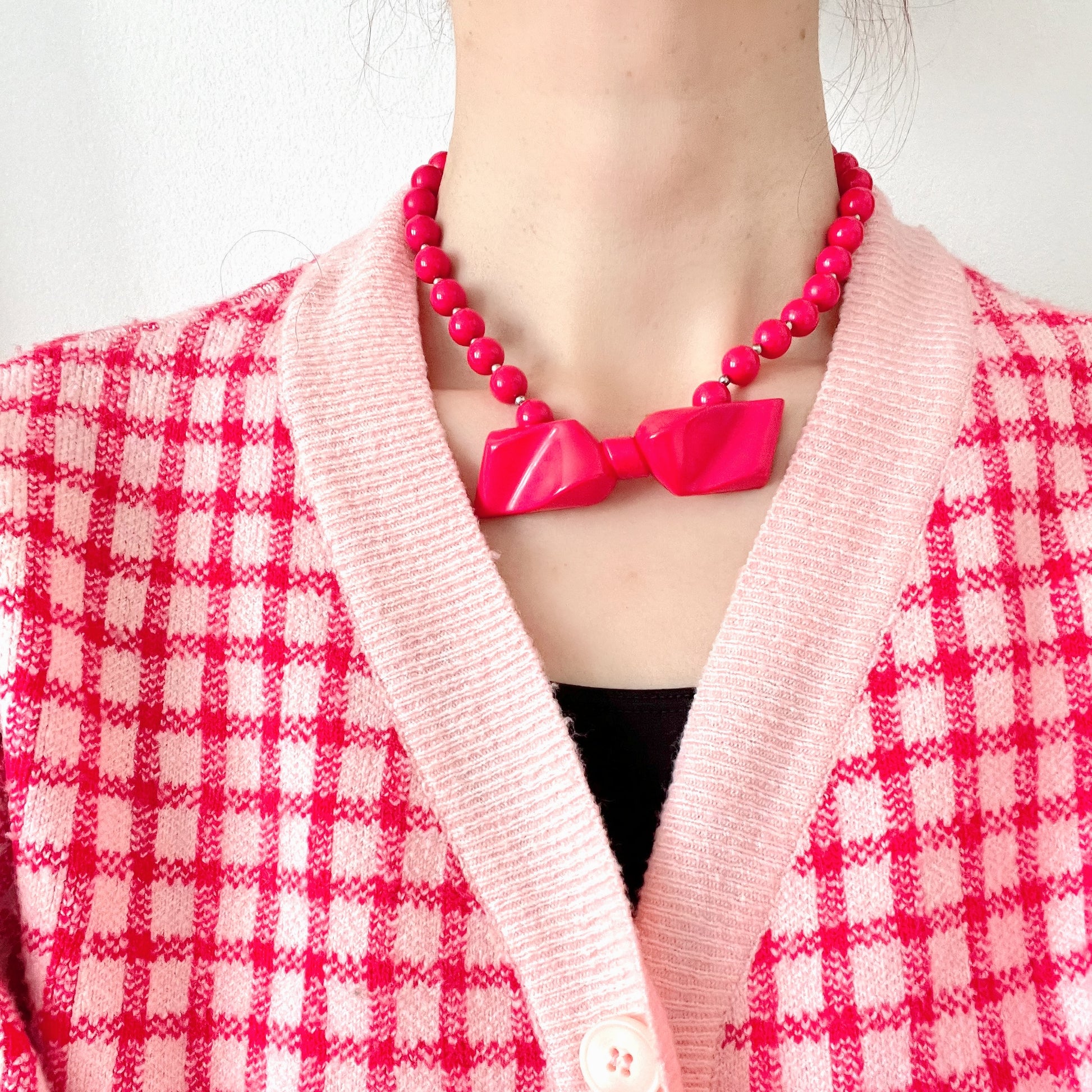 Vintage necklace featuring bright red plastic beads and a bow motif. 鮮やかなプラスチックのレッドビーズとリボンモチーフのネックレス。