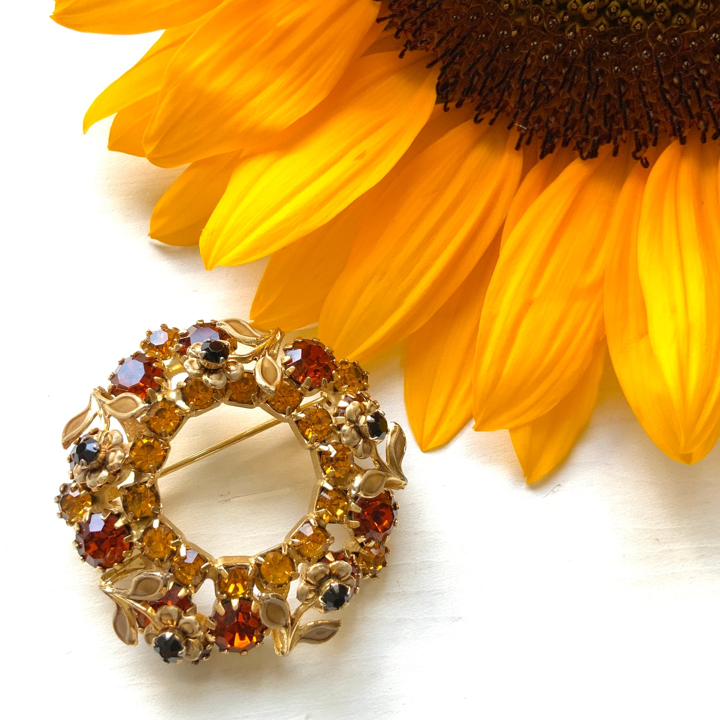 Wreath brooch with amber rhinestones and a petite beige enamel flower. 小さなベージュのエナメルフラワーとアンバーラインストーンのリースブローチ。 