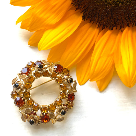 Wreath brooch with amber rhinestones and a petite beige enamel flower. 小さなベージュのエナメルフラワーとアンバーラインストーンのリースブローチ。 