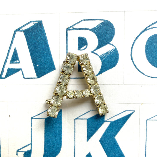 A brooch in the shape of the letter “A”, set with clear rhinestones. クリアラインストーンで”A”を象ったブローチ。 