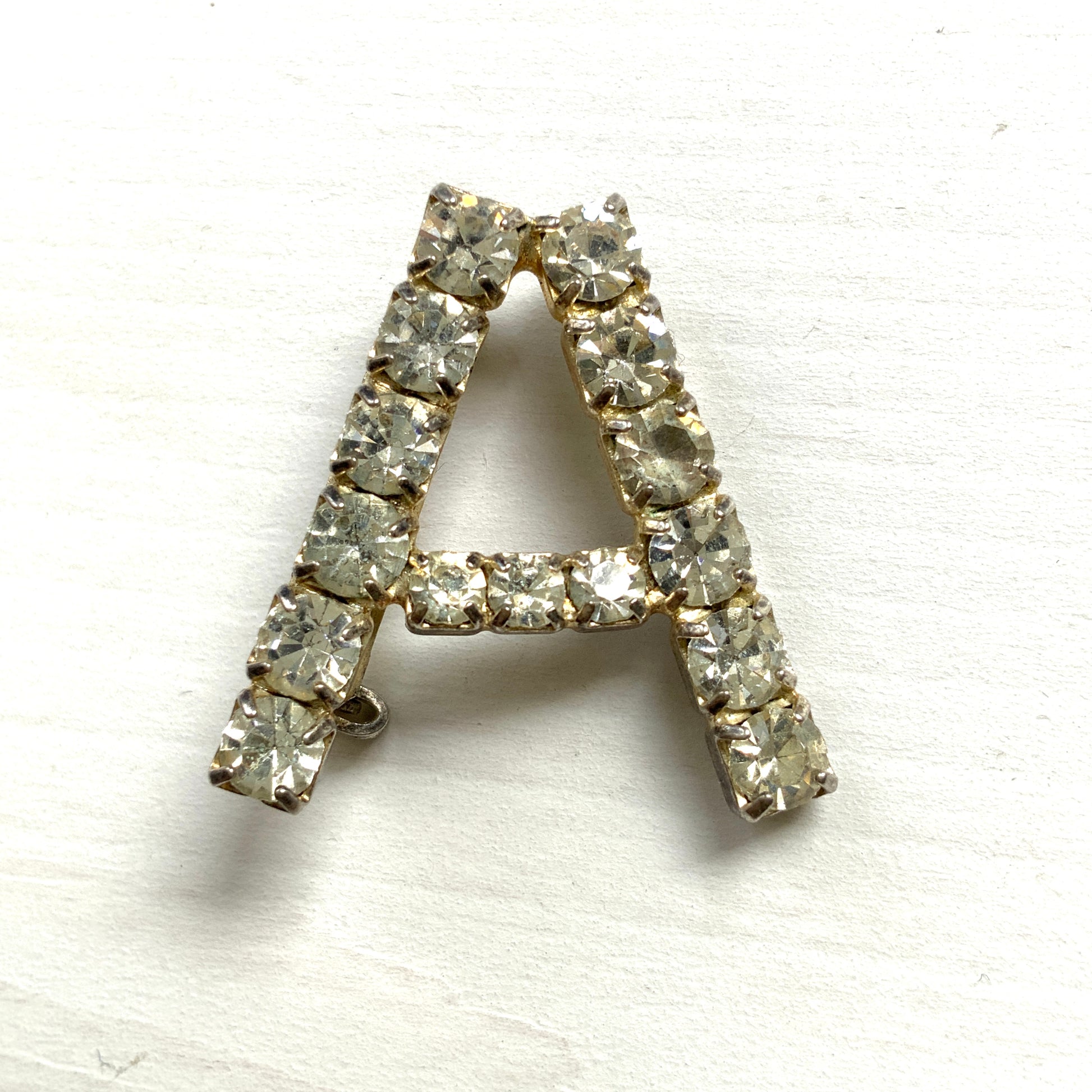 A brooch in the shape of the letter “A”, set with clear rhinestones. クリアラインストーンで”A”を象ったブローチ。 
