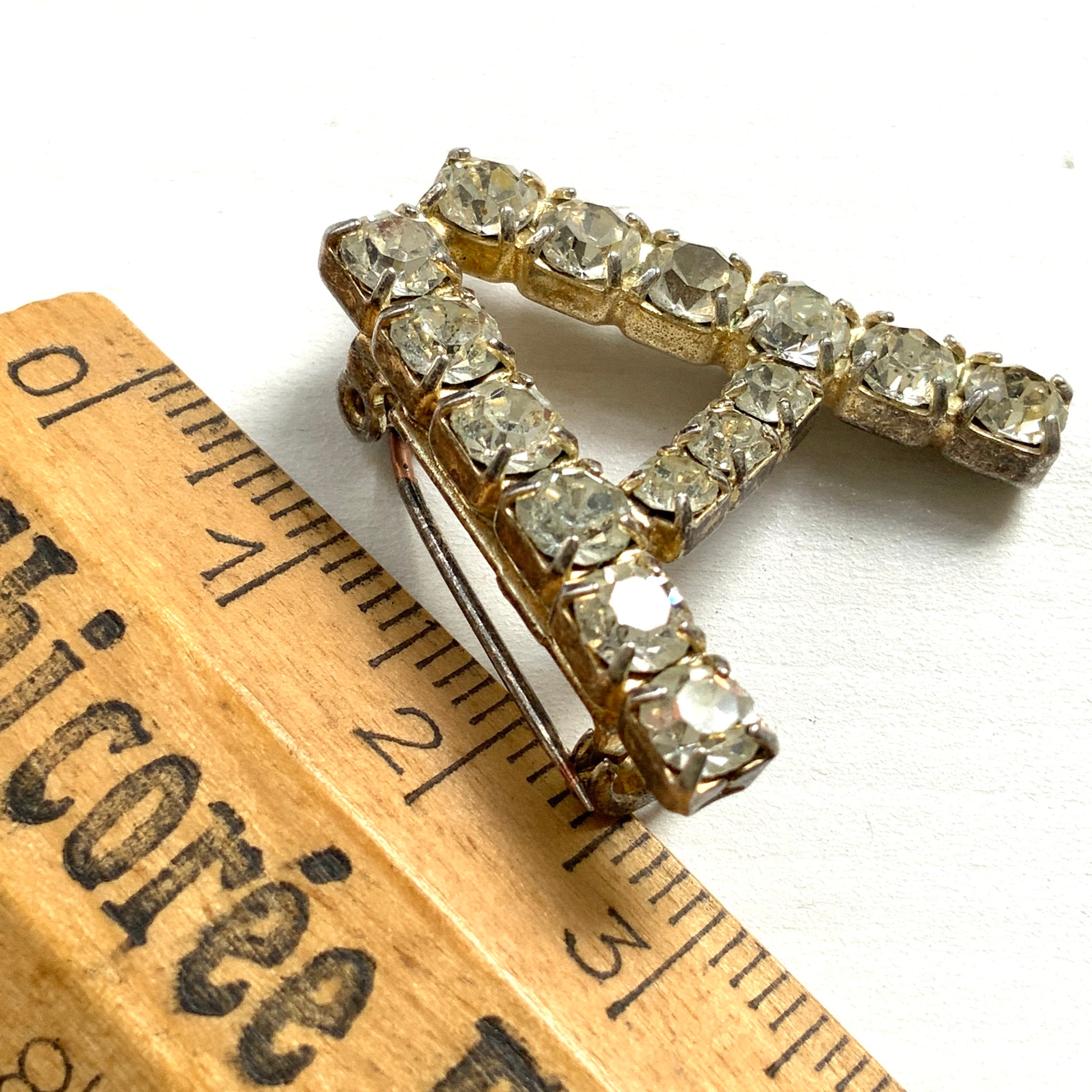 A brooch in the shape of the letter “A”, set with clear rhinestones. クリアラインストーンで”A”を象ったブローチ。 