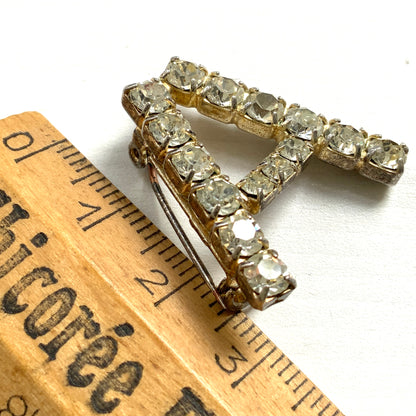 A brooch in the shape of the letter “A”, set with clear rhinestones. クリアラインストーンで”A”を象ったブローチ。 