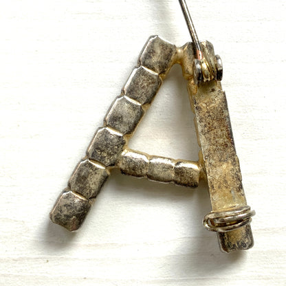 A brooch in the shape of the letter “A”, set with clear rhinestones. クリアラインストーンで”A”を象ったブローチ。 