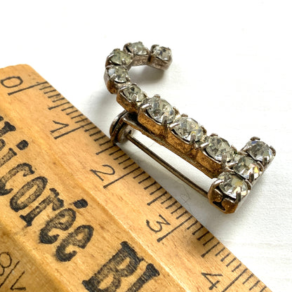 A brooch in the shape of the letter “J”, set with clear rhinestones. クリアラインストーンで”J”を象ったブローチ。