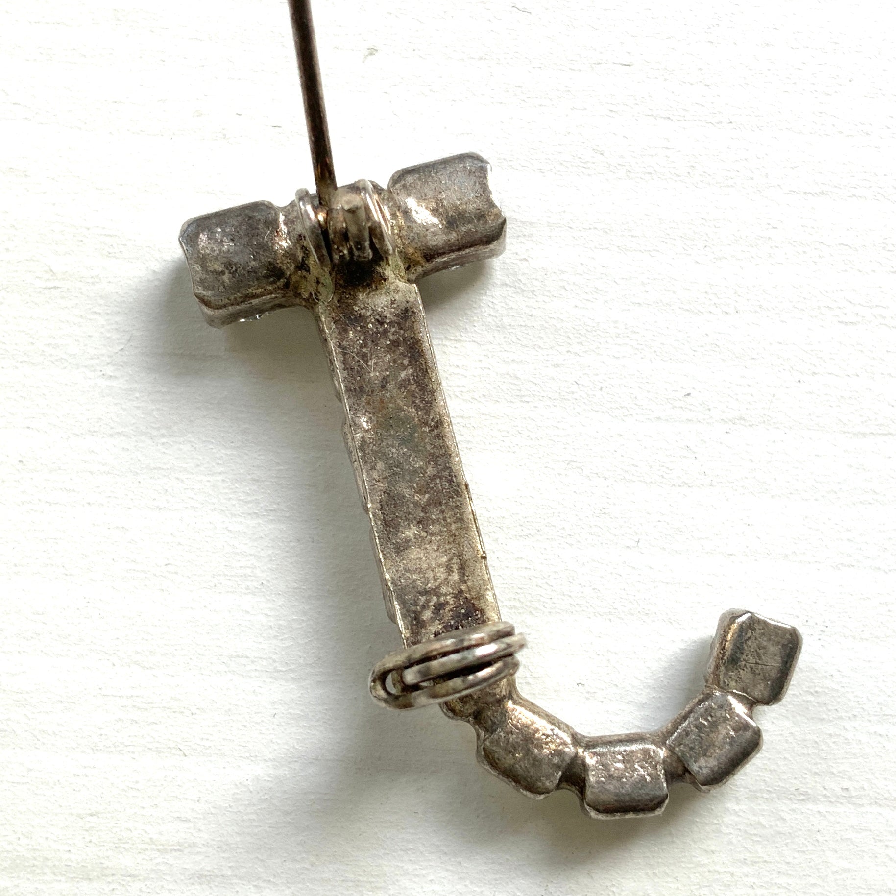 A brooch in the shape of the letter “J”, set with clear rhinestones. クリアラインストーンで”J”を象ったブローチ。