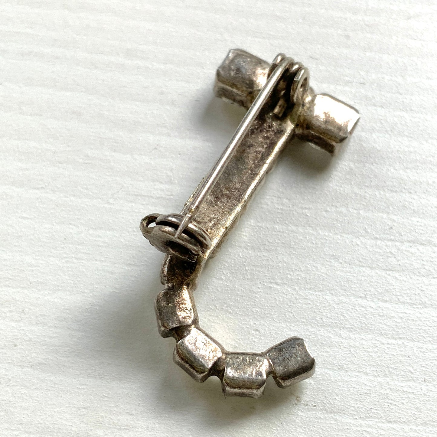 A brooch in the shape of the letter “J”, set with clear rhinestones. クリアラインストーンで”J”を象ったブローチ。