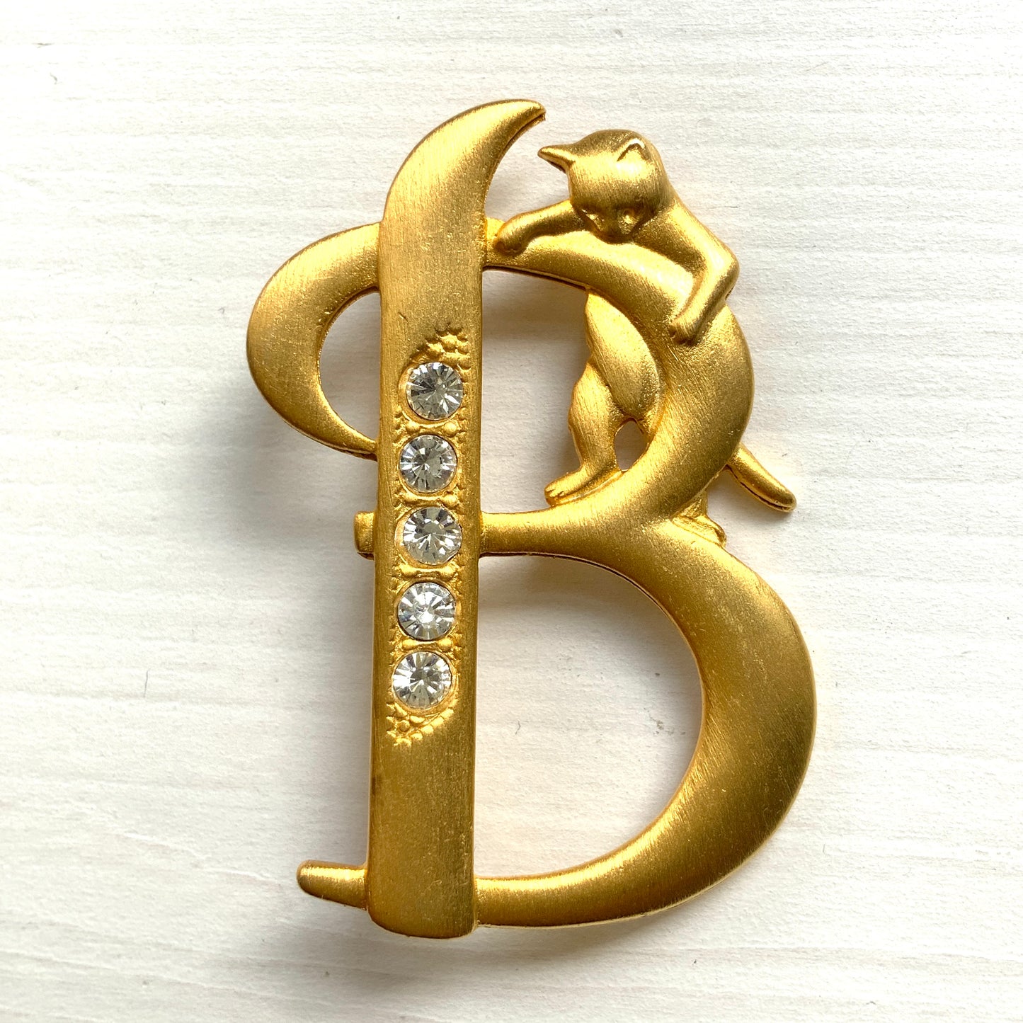 A gold-tone brooch in the shape of the letter “B”, with an adorable kitten clinging to it. かわいい子猫がつかまってる、ゴールドトーンのBのブローチ。