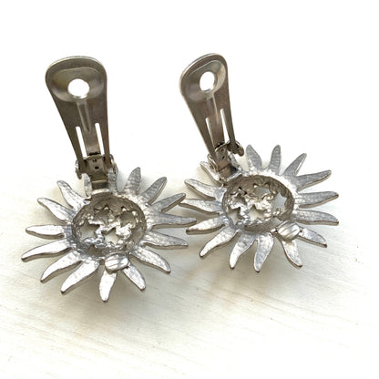 Clip-on earrings featuring a silver-tone sun motif with star-shaped cut-outs. シルバートーンの太陽モチーフに、星型のカットアウトが施されたクリップイヤリング。