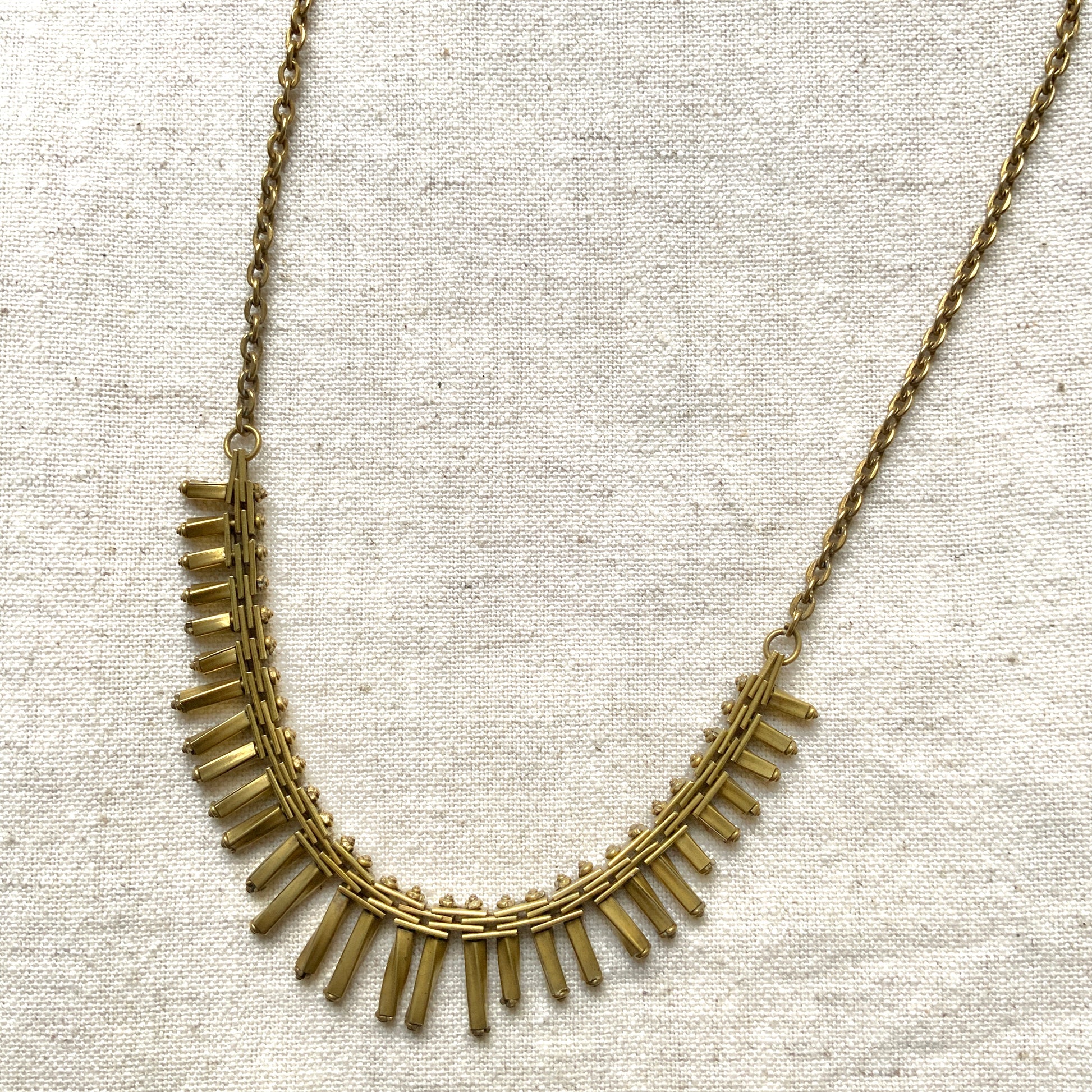 Gold-tone necklace featuring an eye-catching design of elongated twisted bars. 細長いゴールドパーツを並べたデザインが印象的な、ゴールドトーンのネックレス。