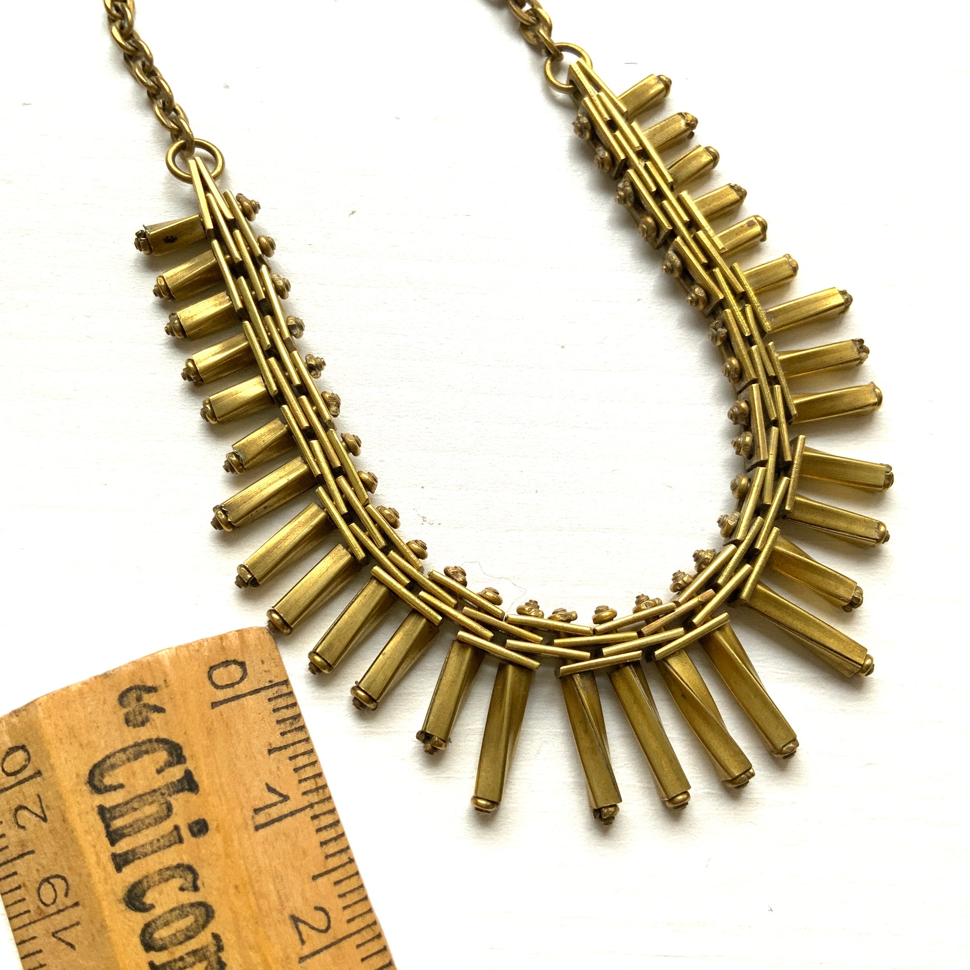 Gold-tone necklace featuring an eye-catching design of elongated twisted bars. 細長いゴールドパーツを並べたデザインが印象的な、ゴールドトーンのネックレス。