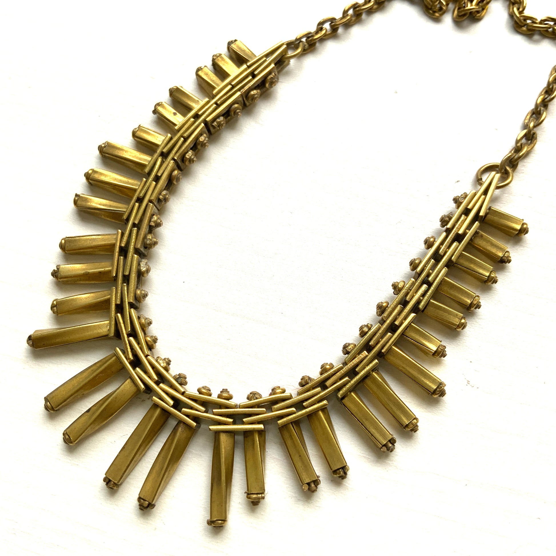 Gold-tone necklace featuring an eye-catching design of elongated twisted bars. 細長いゴールドパーツを並べたデザインが印象的な、ゴールドトーンのネックレス。