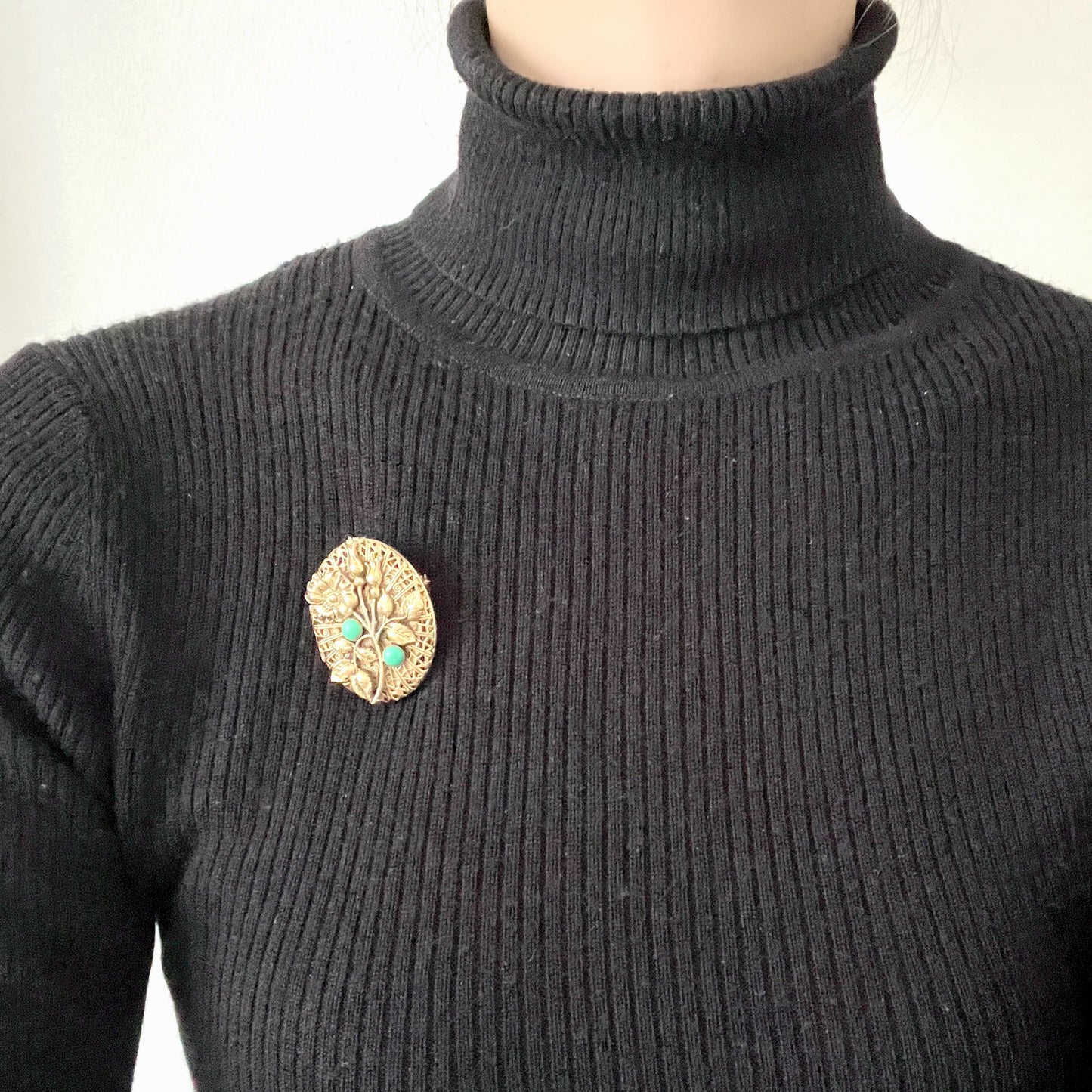 A gold-tone locket brooch featuring a floral motif accented with turquoise blue cabochons.  ゴールドトーンのお花に、ターコイズブルーのカボションが映えるロケットブローチ。