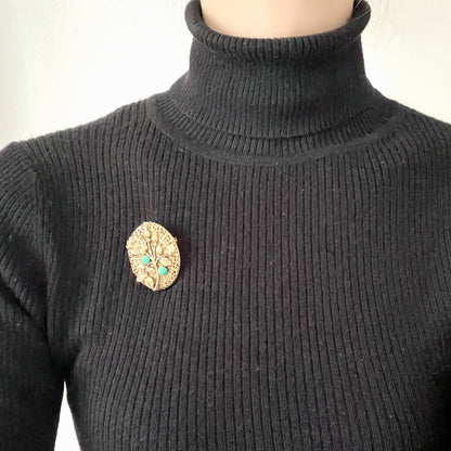 A gold-tone locket brooch featuring a floral motif accented with turquoise blue cabochons.  ゴールドトーンのお花に、ターコイズブルーのカボションが映えるロケットブローチ。