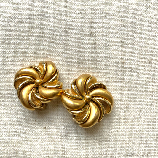 Gold-tone swirl clip-on earrings with curved, sculptural lines. 曲線的なスワールモチーフが印象的な、ゴールドトーンのクリップイヤリング。