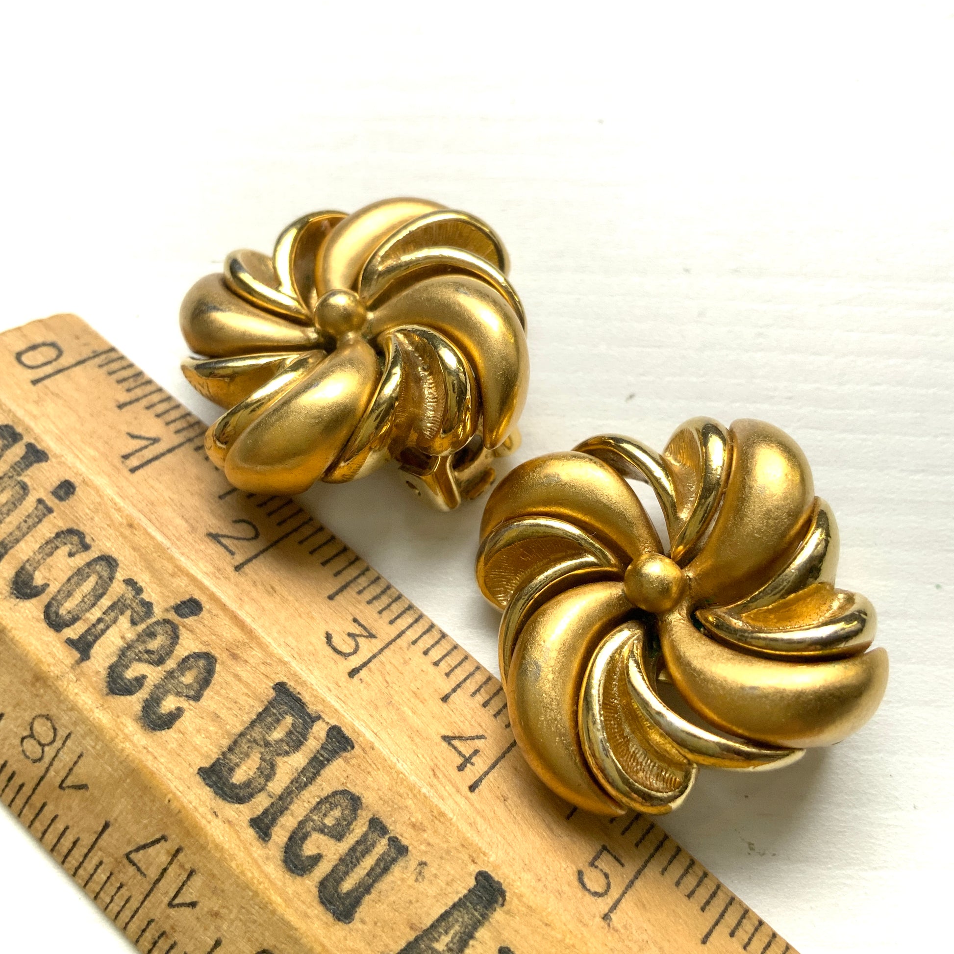 Gold-tone swirl clip-on earrings with curved, sculptural lines. 曲線的なスワールモチーフが印象的な、ゴールドトーンのクリップイヤリング。