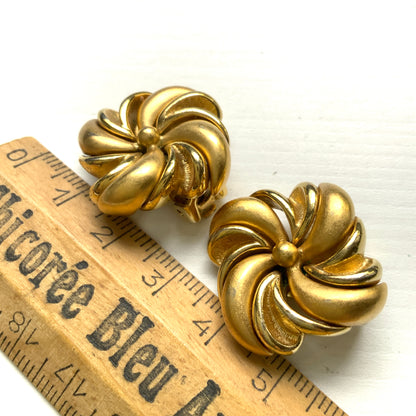 Gold-tone swirl clip-on earrings with curved, sculptural lines. 曲線的なスワールモチーフが印象的な、ゴールドトーンのクリップイヤリング。