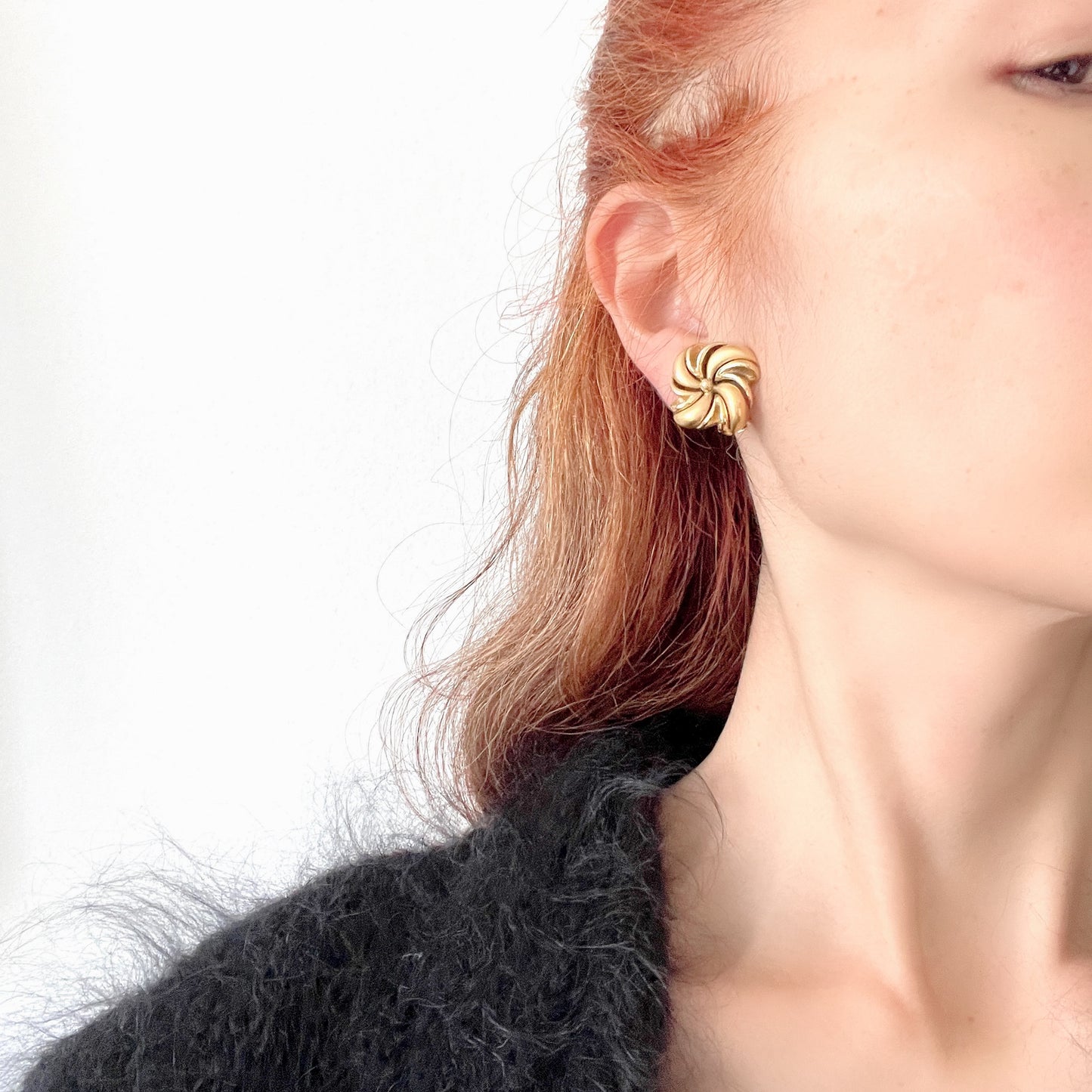 Gold-tone swirl clip-on earrings with curved, sculptural lines. 曲線的なスワールモチーフが印象的な、ゴールドトーンのクリップイヤリング。