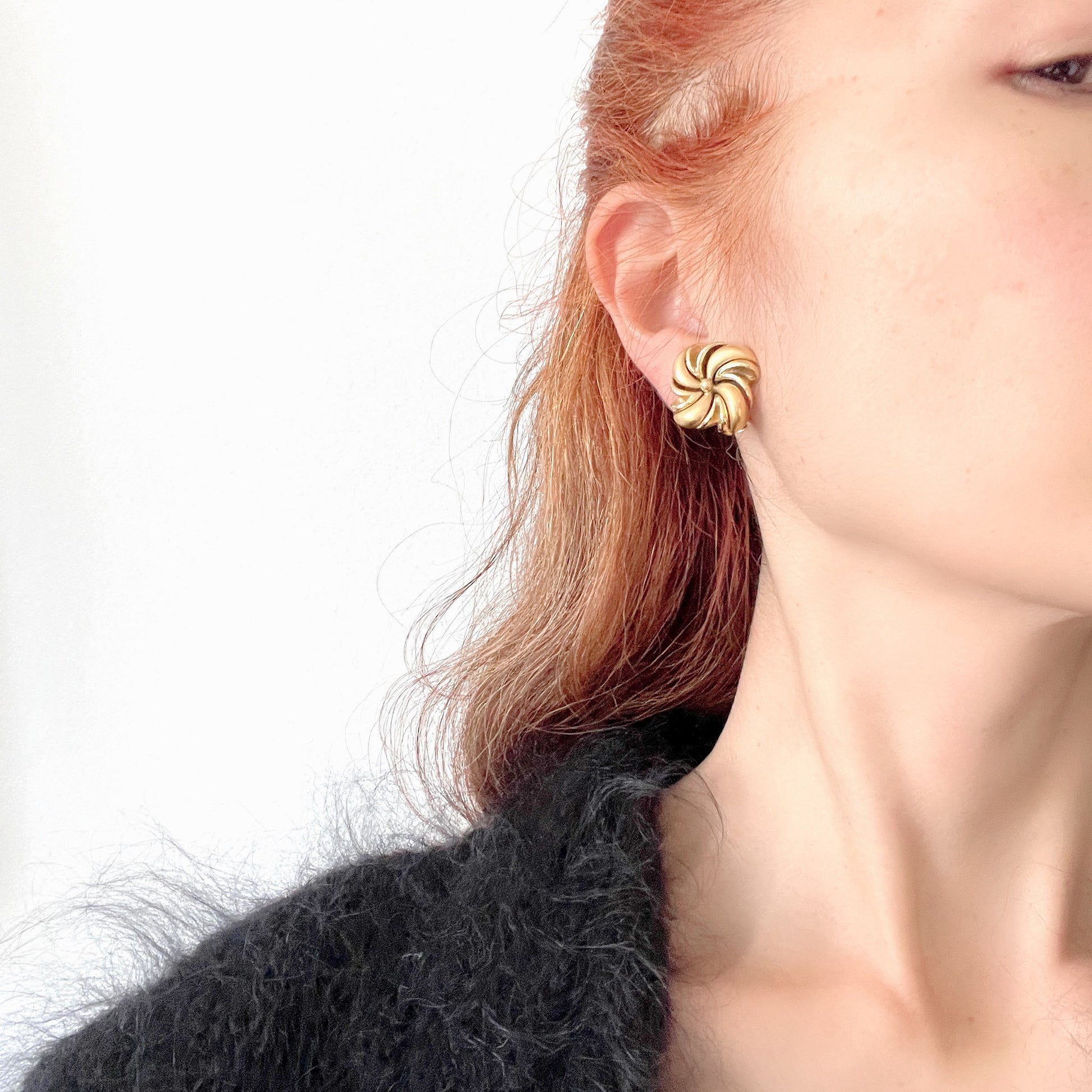 Gold-tone swirl clip-on earrings with curved, sculptural lines. 曲線的なスワールモチーフが印象的な、ゴールドトーンのクリップイヤリング。