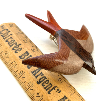 A wooden swallow brooch made from different shades of natural wood. 色味の異なる木材を組み合わせて作られた、ツバメモチーフのウッドブローチ。
