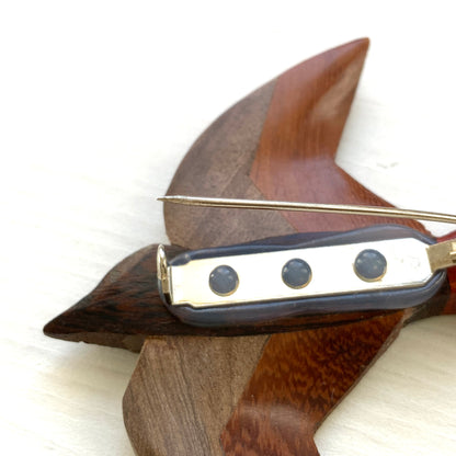 A wooden swallow brooch made from different shades of natural wood. 色味の異なる木材を組み合わせて作られた、ツバメモチーフのウッドブローチ。