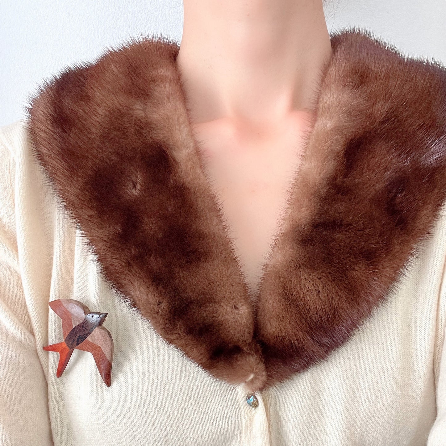 A wooden swallow brooch made from different shades of natural wood. 色味の異なる木材を組み合わせて作られた、ツバメモチーフのウッドブローチ。