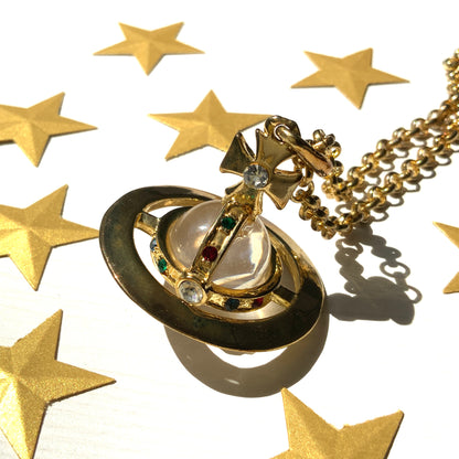 A striking pendant necklace featuring a decorative orb encircled by a metal hoop, resembling the rings of Saturn. カラフルなストーンで飾られた宝珠（キリスト教圏で、十字架をのせた球体として王権の象徴に用いられるモチーフ）を、まるで土星の輪のようなメタルフープで囲んだデザインのペンダントネックレスです。