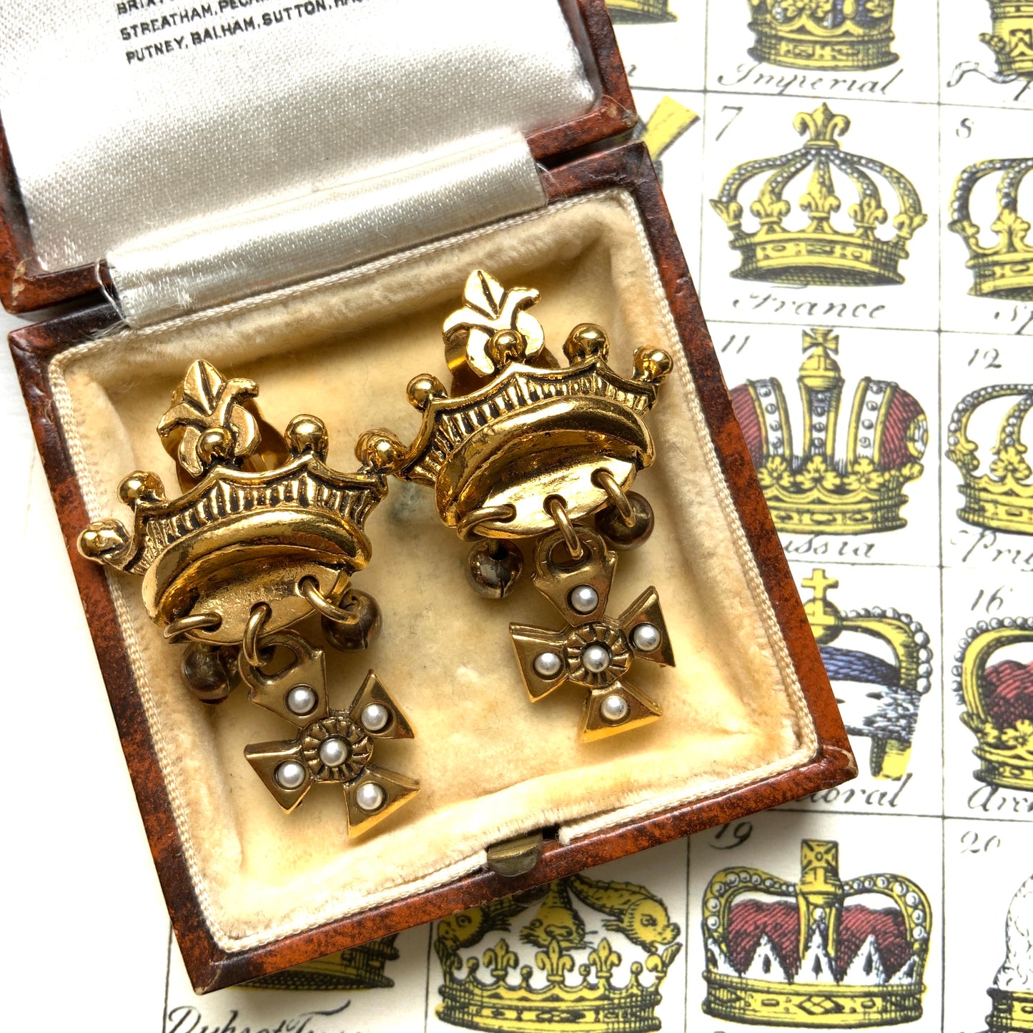 Gold-tone crown clip-on earrings with a Maltese cross charm. ゴールドトーンのクラウンに、マルティーズクロスがゆれるクリップイヤリング。 