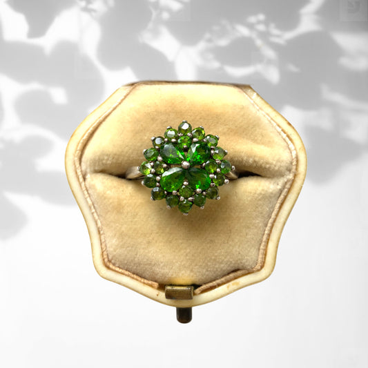 A silver ring set with vivid green diopside stones arranged in a floral design. 鮮やかなグリーンのダイオブサイドが花のように並んだシルバーリング。 