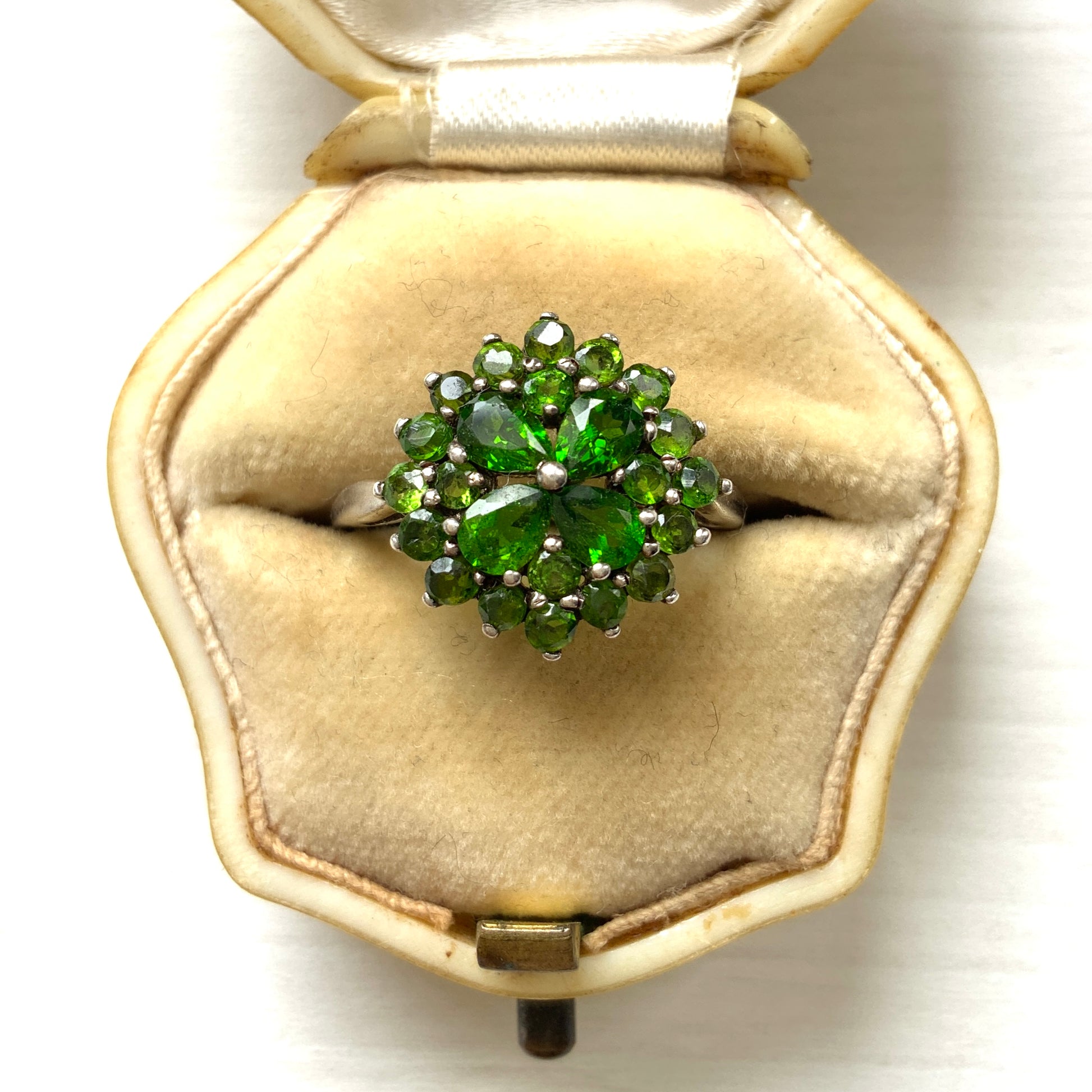 A silver ring set with vivid green diopside stones arranged in a floral design. 鮮やかなグリーンのダイオブサイドが花のように並んだシルバーリング。 
