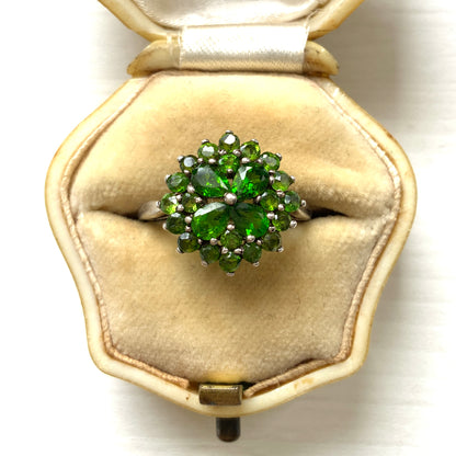 A silver ring set with vivid green diopside stones arranged in a floral design. 鮮やかなグリーンのダイオブサイドが花のように並んだシルバーリング。 