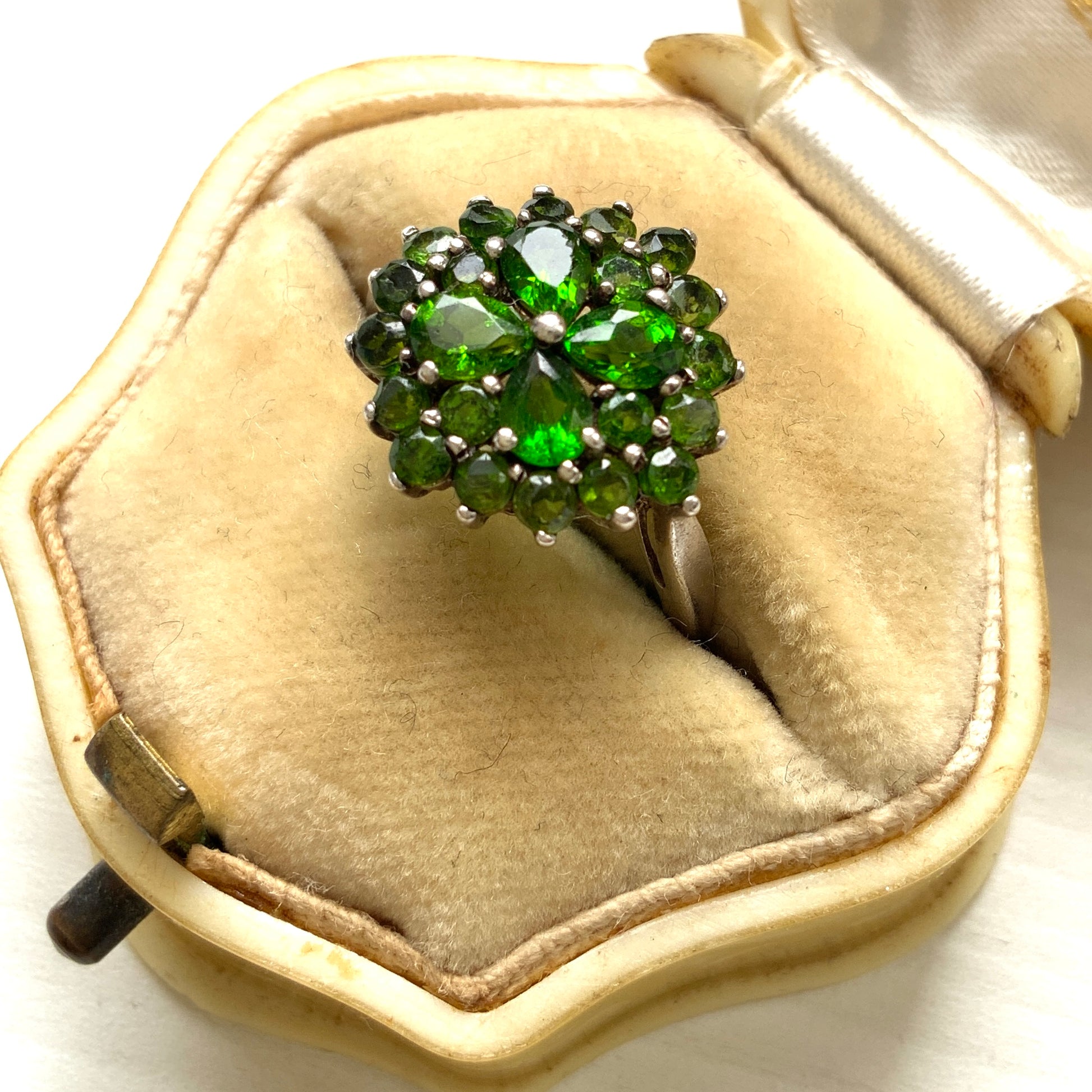 A silver ring set with vivid green diopside stones arranged in a floral design. 鮮やかなグリーンのダイオブサイドが花のように並んだシルバーリング。 
