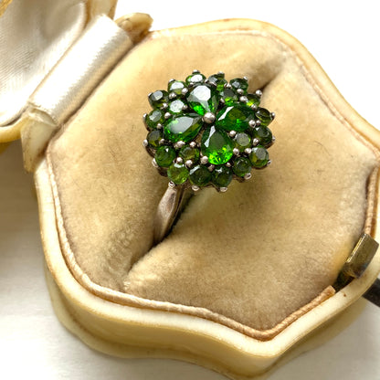 A silver ring set with vivid green diopside stones arranged in a floral design. 鮮やかなグリーンのダイオブサイドが花のように並んだシルバーリング。 