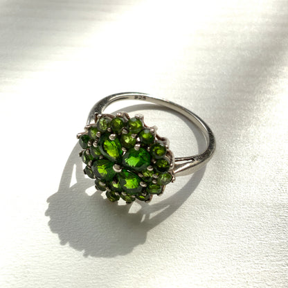 A silver ring set with vivid green diopside stones arranged in a floral design. 鮮やかなグリーンのダイオブサイドが花のように並んだシルバーリング。 