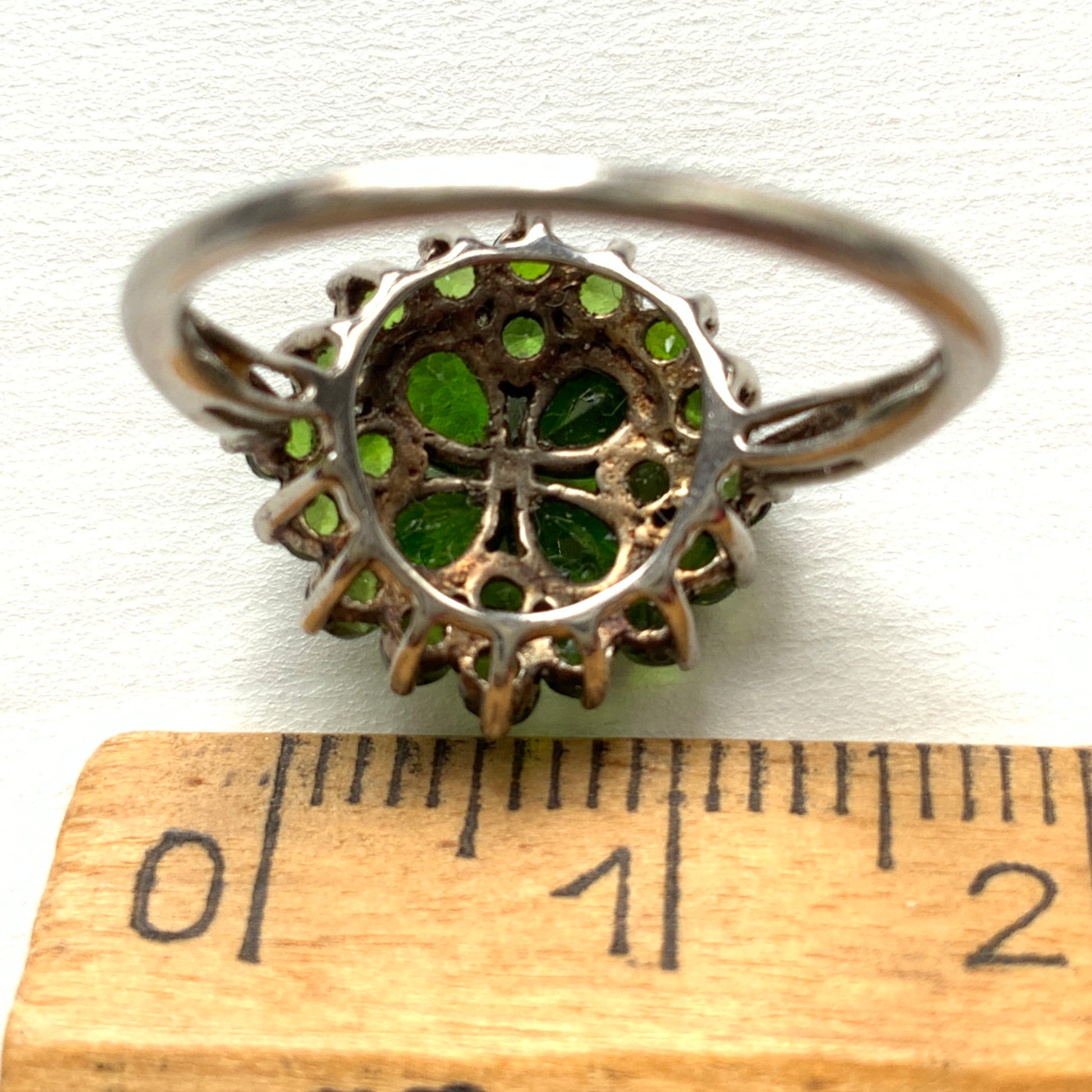 A silver ring set with vivid green diopside stones arranged in a floral design. 鮮やかなグリーンのダイオブサイドが花のように並んだシルバーリング。 