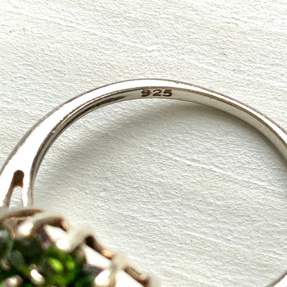 A silver ring set with vivid green diopside stones arranged in a floral design. 鮮やかなグリーンのダイオブサイドが花のように並んだシルバーリング。 
