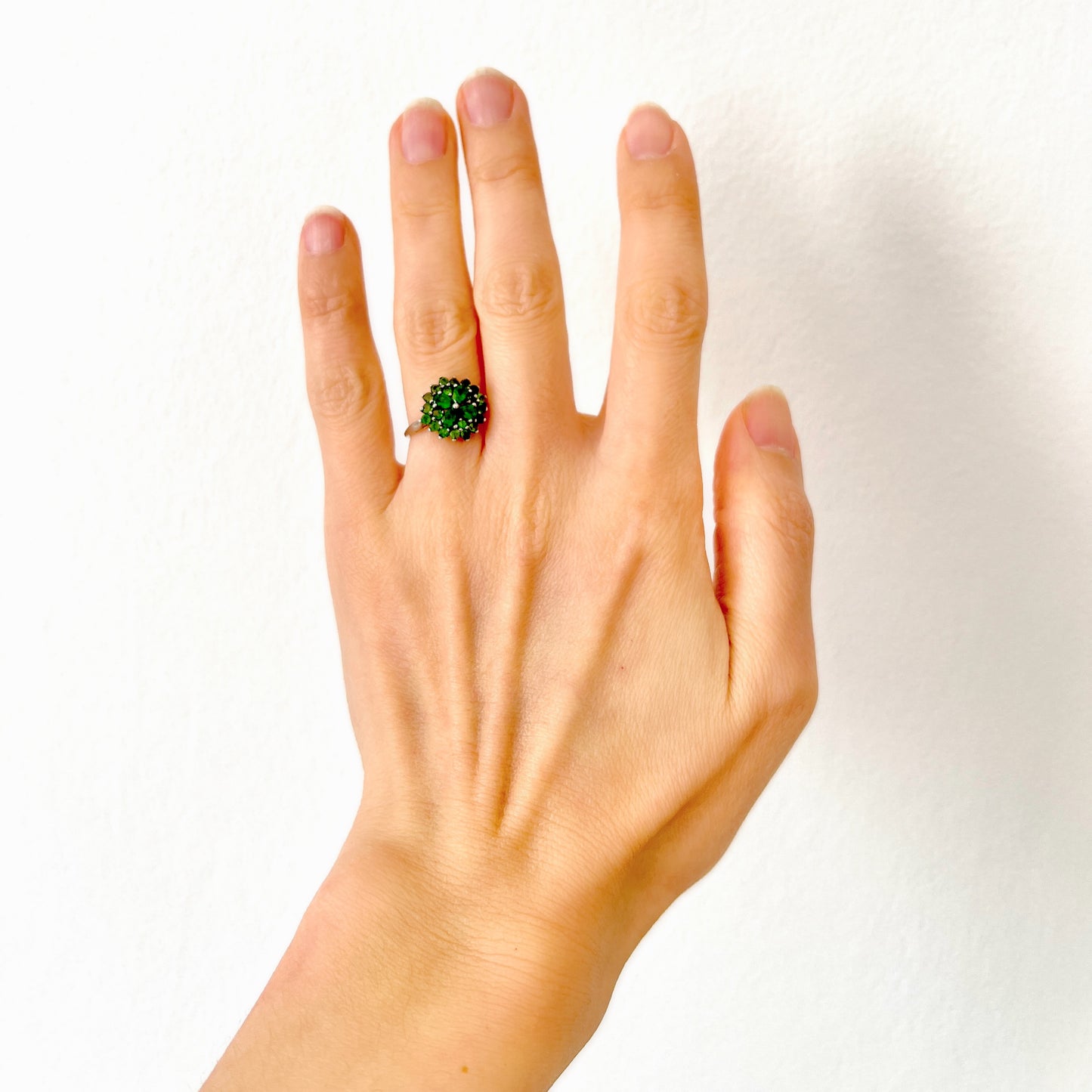 A silver ring set with vivid green diopside stones arranged in a floral design. 鮮やかなグリーンのダイオブサイドが花のように並んだシルバーリング。 