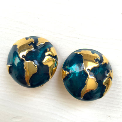 Clip-on earrings featuring a globe design with gold tone continents over a dome of deep ocean blue enamel.  深い海の色のエナメルドームにゴールドトーンで大陸をあしらった地球のクリップイヤリング。