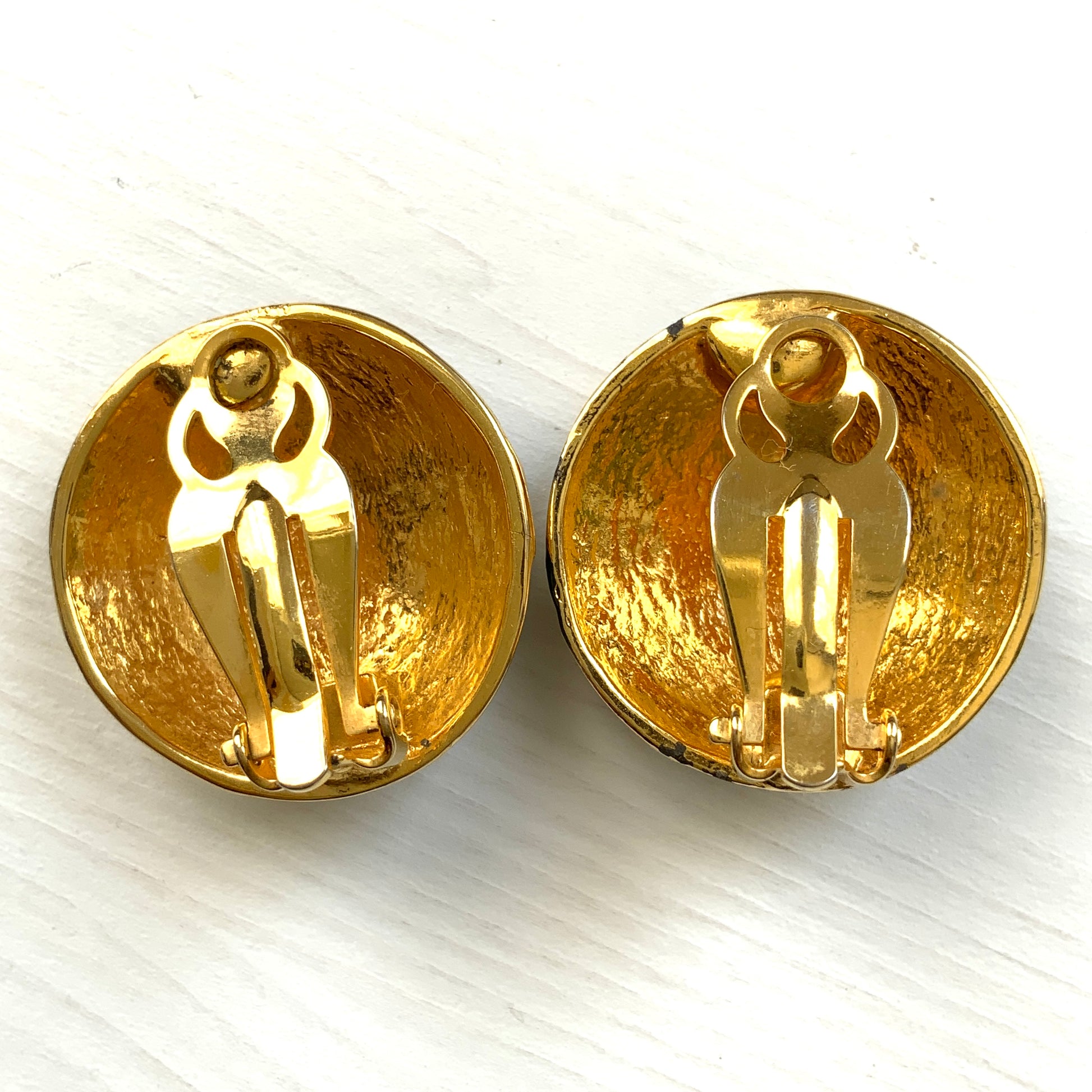 Clip-on earrings featuring a globe design with gold tone continents over a dome of deep ocean blue enamel.  深い海の色のエナメルドームにゴールドトーンで大陸をあしらった地球のクリップイヤリング。
