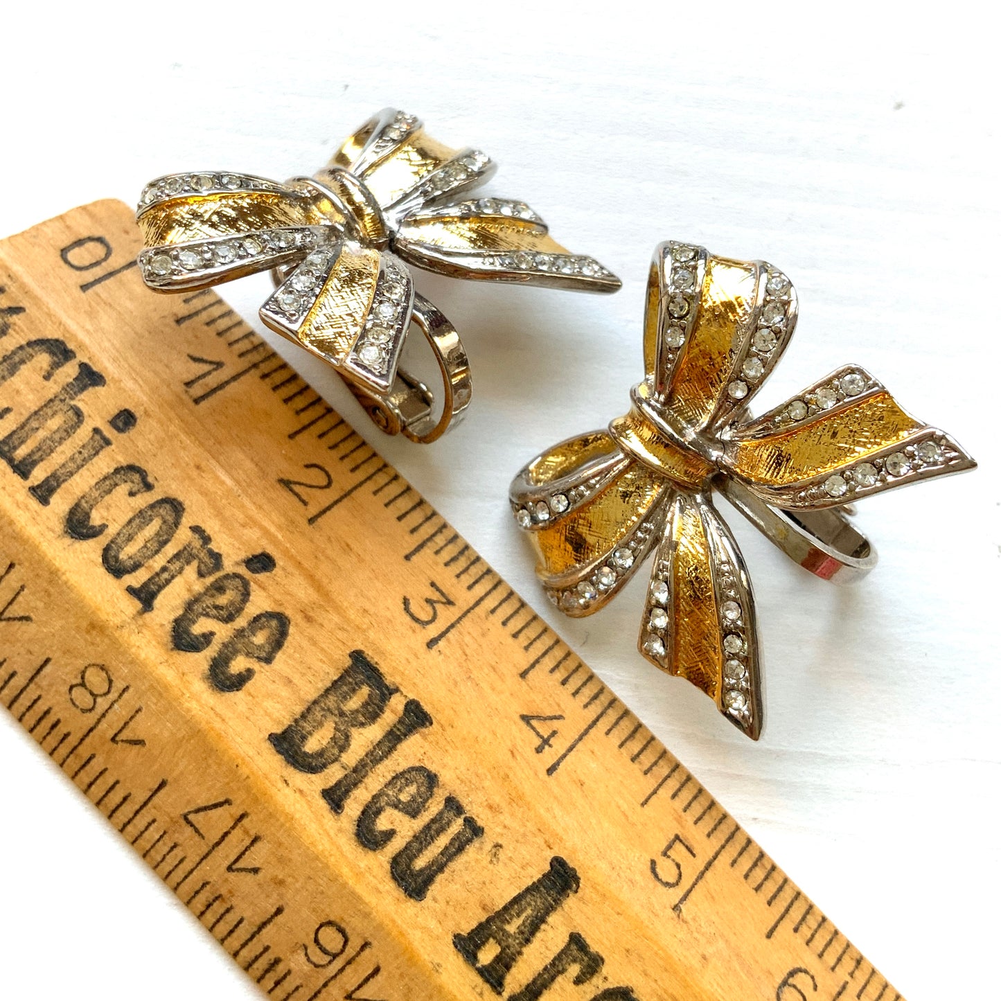 Vintage clip-on earrings in a bow design featuring both gold-tone and silver-tone metal. ゴールドトーンとシルバートーンのリボンのクリップイヤリング。 